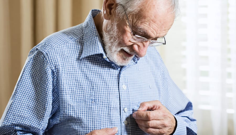 Elderly person showing difficulty with buttoning their clothing, demonstrating early signs of Alzheimer's